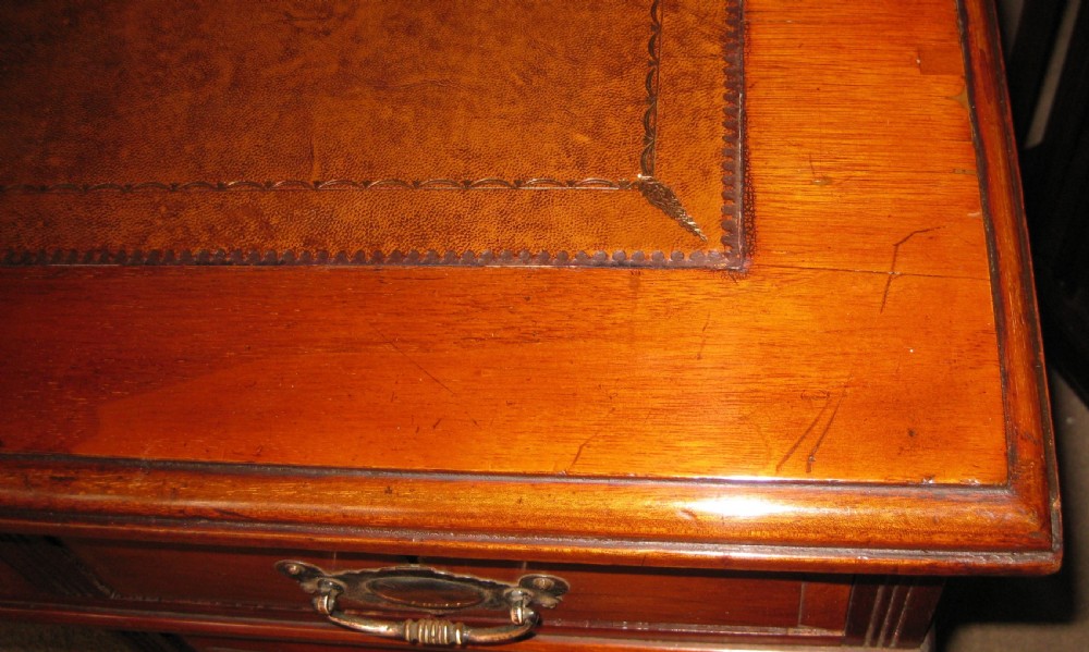 A late Victorian golden walnut pedestal desk featuring a leather-inset writing surface, nine drawers with brass handles, and turned feet. View IV