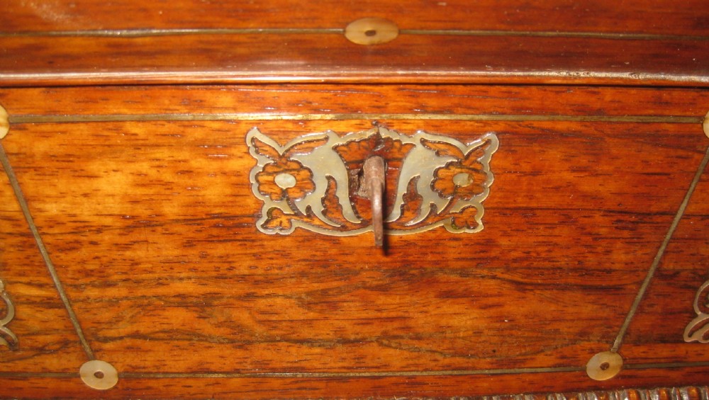 An antique sarcophagus-shaped rosewood sewing box featuring floral brass and mother-of-pearl inlays, carved gadrooned borders, and bun feet. View V