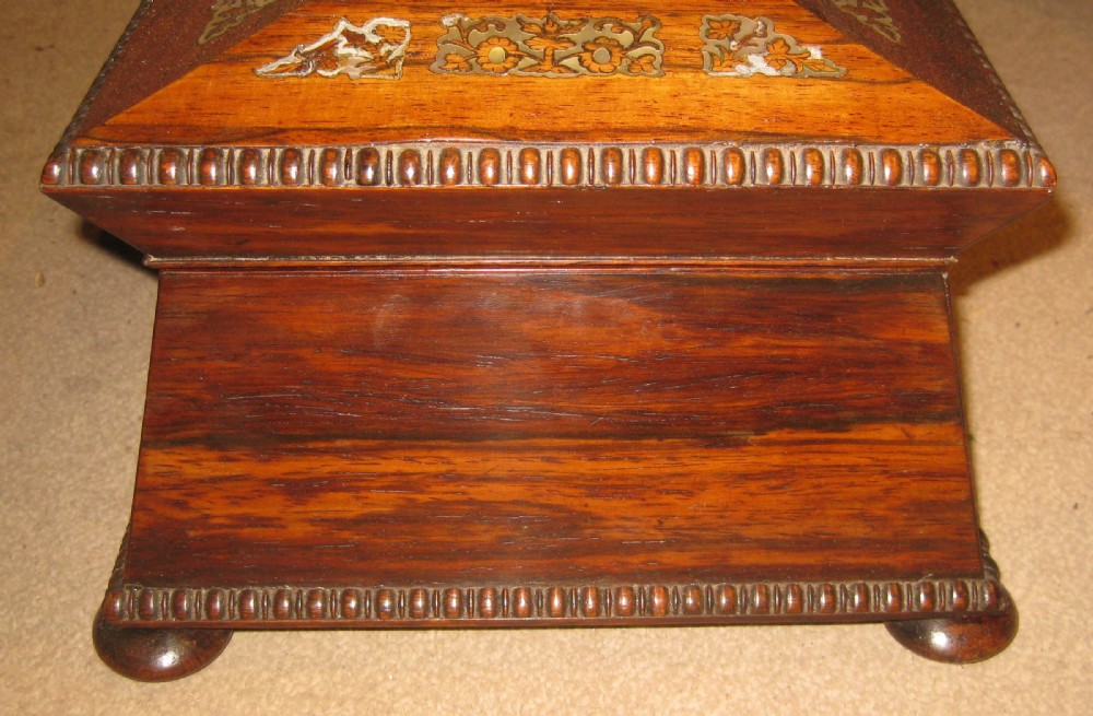 An antique sarcophagus-shaped rosewood sewing box featuring floral brass and mother-of-pearl inlays, carved gadrooned borders, and bun feet. View VII