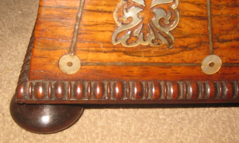 An antique sarcophagus-shaped rosewood sewing box featuring floral brass and mother-of-pearl inlays, carved gadrooned borders, and bun feet. View IX