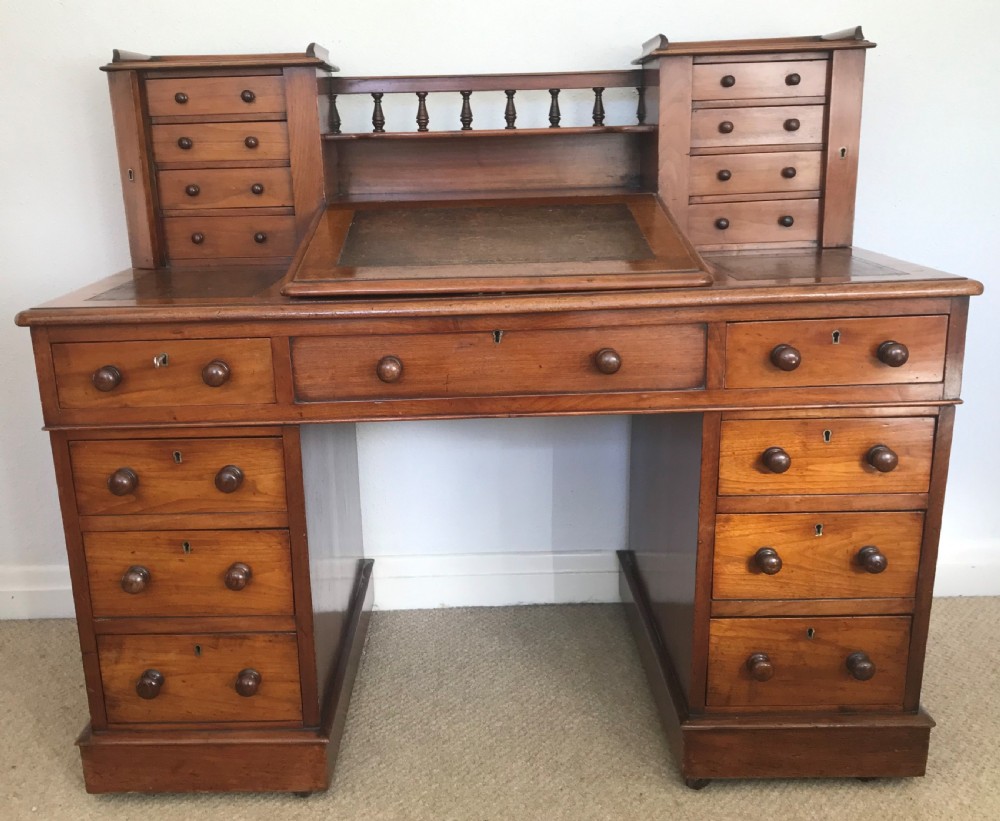 A Victorian golden walnut Dickens desk featuring a central sloped leather writing surface flanked by raised side drawers and a spindle gallery above twin drawer pedestals. View II