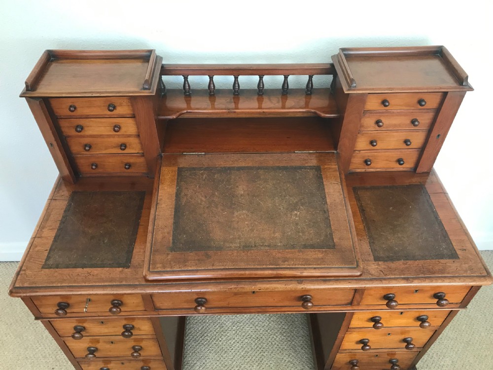 A Victorian golden walnut Dickens desk featuring a central sloped leather writing surface flanked by raised side drawers and a spindle gallery above twin drawer pedestals. View III