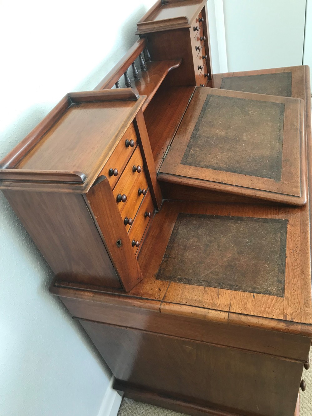 A Victorian golden walnut Dickens desk featuring a central sloped leather writing surface flanked by raised side drawers and a spindle gallery above twin drawer pedestals. View IV
