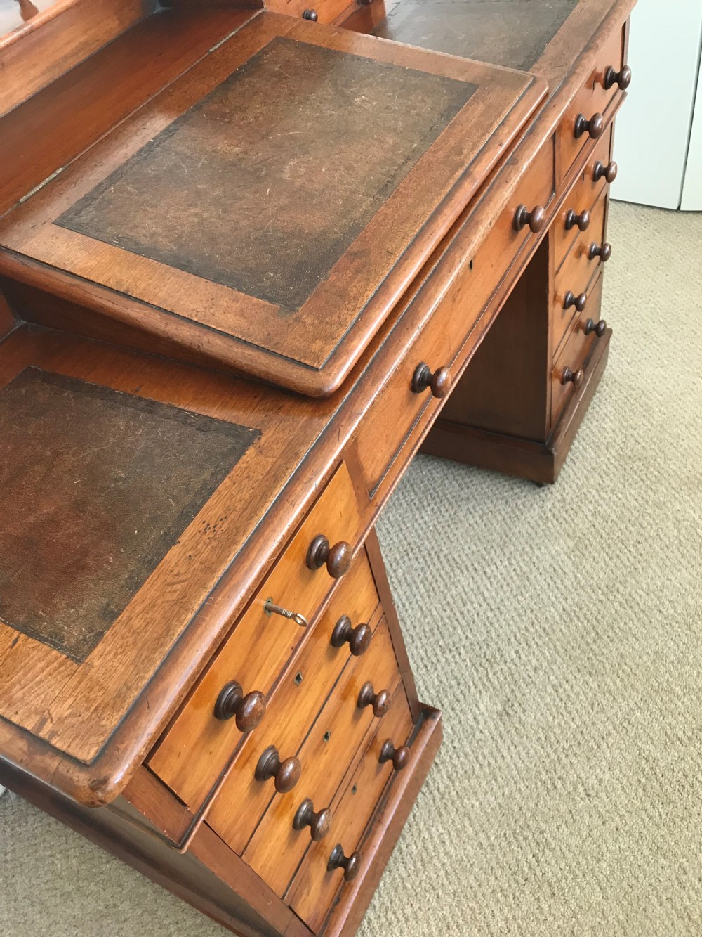 A Victorian golden walnut Dickens desk featuring a central sloped leather writing surface flanked by raised side drawers and a spindle gallery above twin drawer pedestals. View V