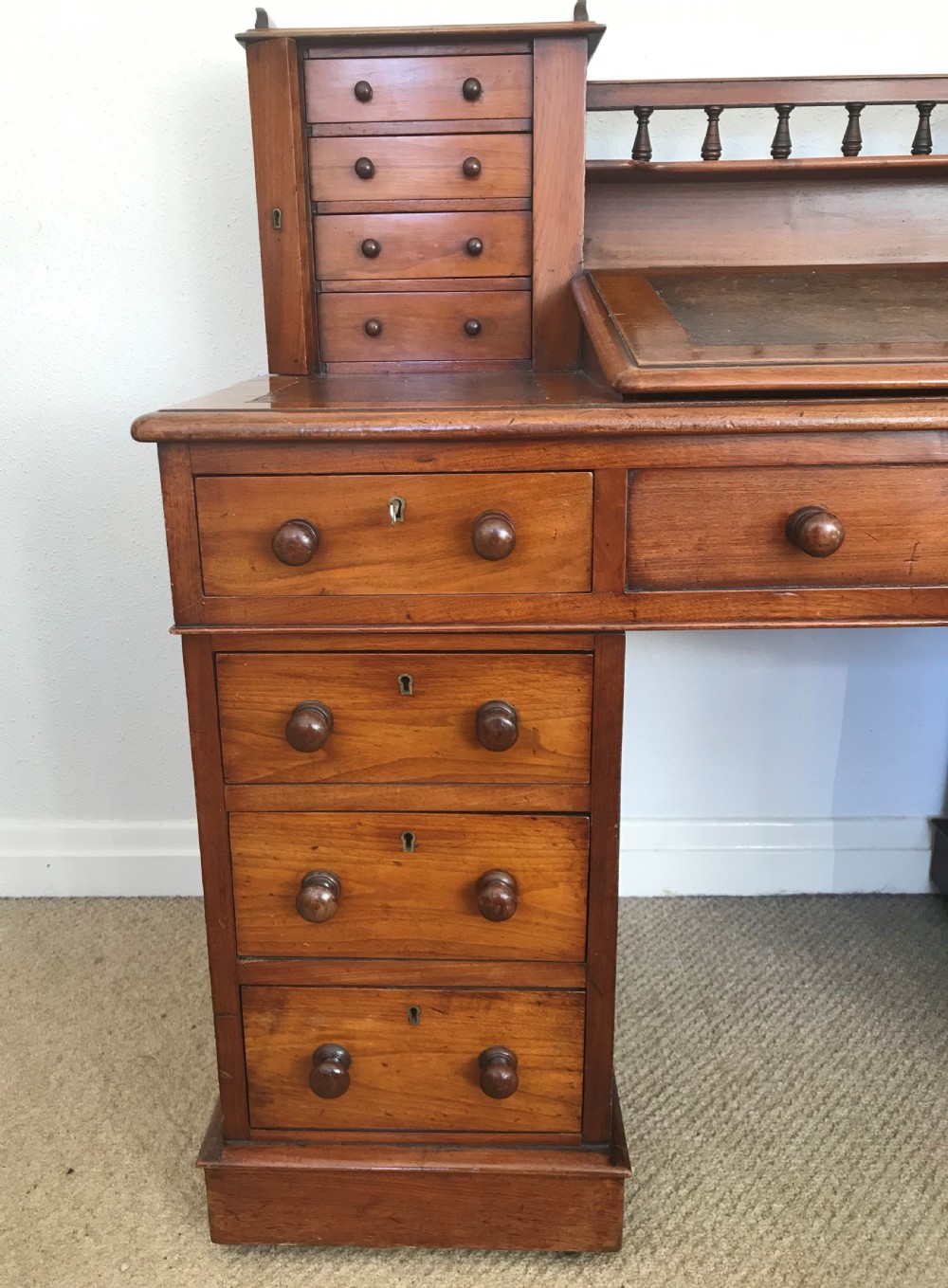 A Victorian golden walnut Dickens desk featuring a central sloped leather writing surface flanked by raised side drawers and a spindle gallery above twin drawer pedestals. View VII