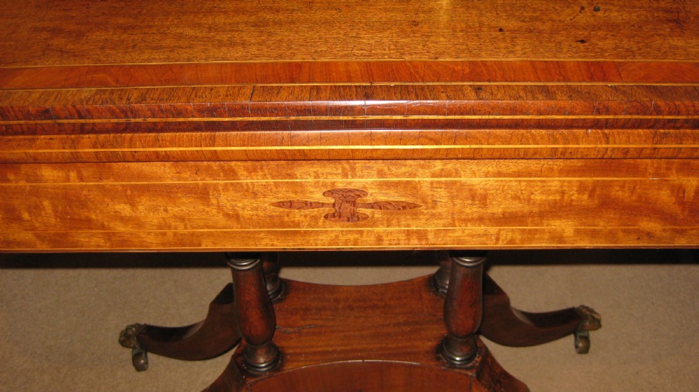 An early Victorian mahogany and rosewood fold-over card table featuring an inlaid frieze, twin turned supports, and splayed legs with brass paw feet. View II