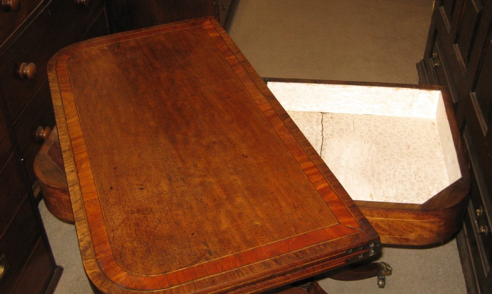 An early Victorian mahogany and rosewood fold-over card table featuring an inlaid frieze, twin turned supports, and splayed legs with brass paw feet. View IV
