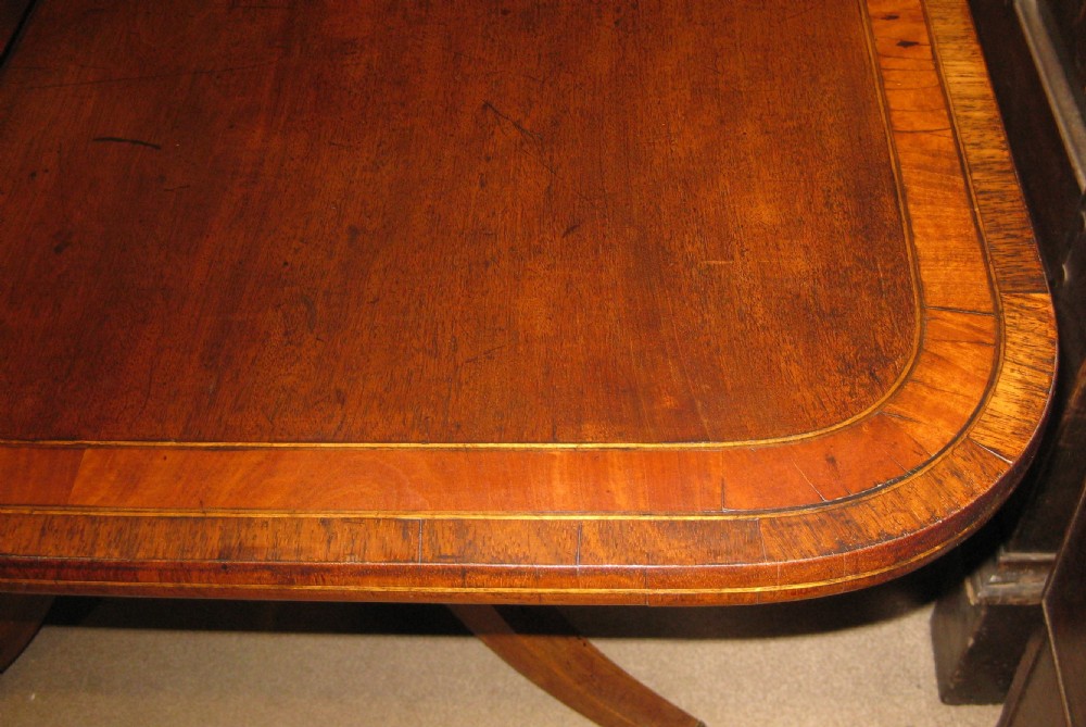 An early Victorian mahogany and rosewood fold-over card table featuring an inlaid frieze, twin turned supports, and splayed legs with brass paw feet. View VII