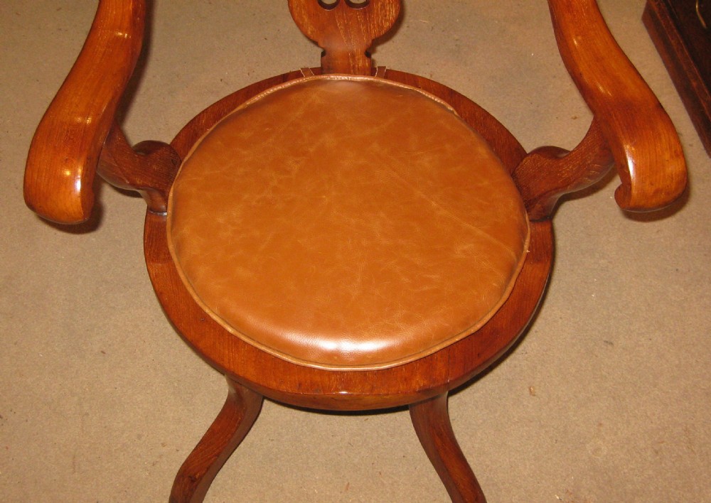A Victorian walnut revolving desk chair featuring a continuous curved backrail, pierced vase splat, shaped saddle seat, and splayed legs. View IV