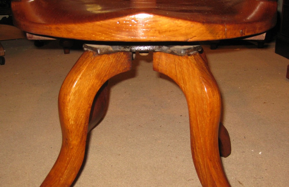 A Victorian walnut revolving desk chair featuring a continuous curved backrail, pierced vase splat, shaped saddle seat, and splayed legs. View VIII