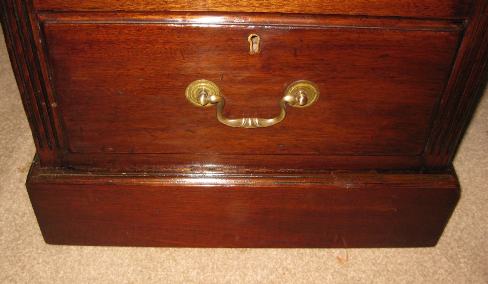 An antique mahogany pedestal desk featuring nine drawers with brass handles and a reddish-brown leather writing surface. View II