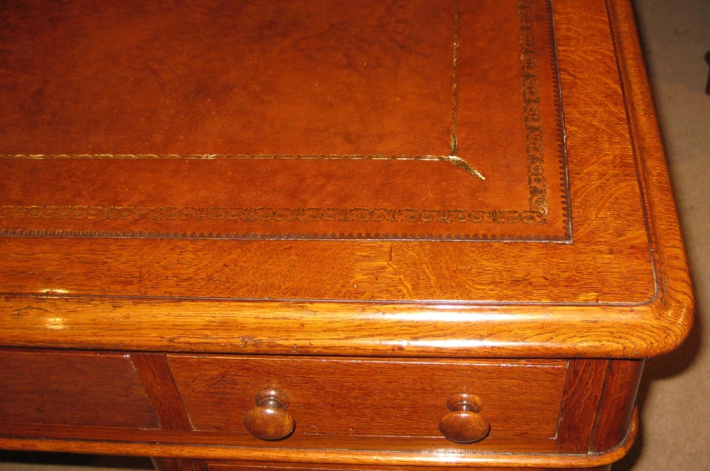A Victorian oak pedestal desk featuring a leather-inlaid writing top, nine drawers with turned wooden knobs, and double plinth bases. View II