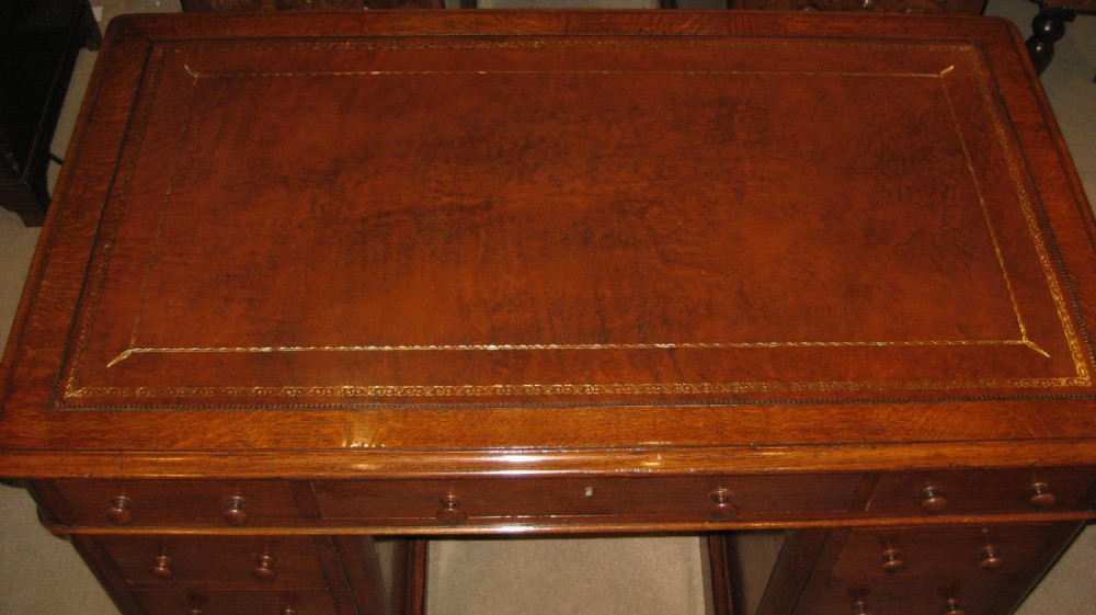 A Victorian oak pedestal desk featuring a leather-inlaid writing top, nine drawers with turned wooden knobs, and double plinth bases. View III