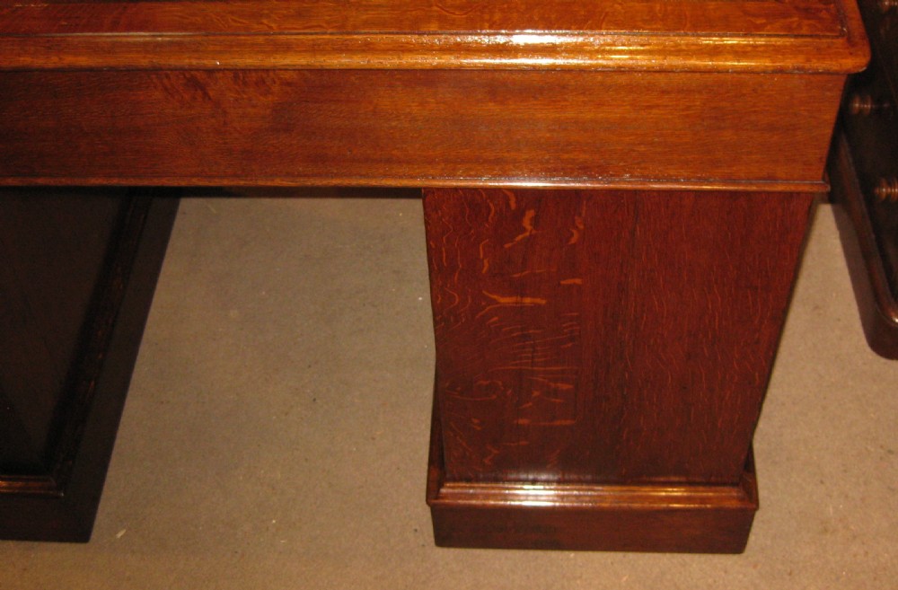 A Victorian oak pedestal desk featuring a leather-inlaid writing top, nine drawers with turned wooden knobs, and double plinth bases. View IX