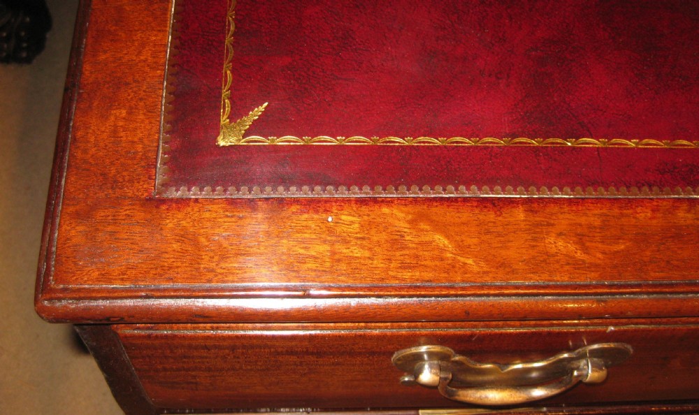 An 18th-century Georgian mahogany kneehole desk featuring a leather inset top, brass swan-neck handles, and flanking columns of drawers. View IV