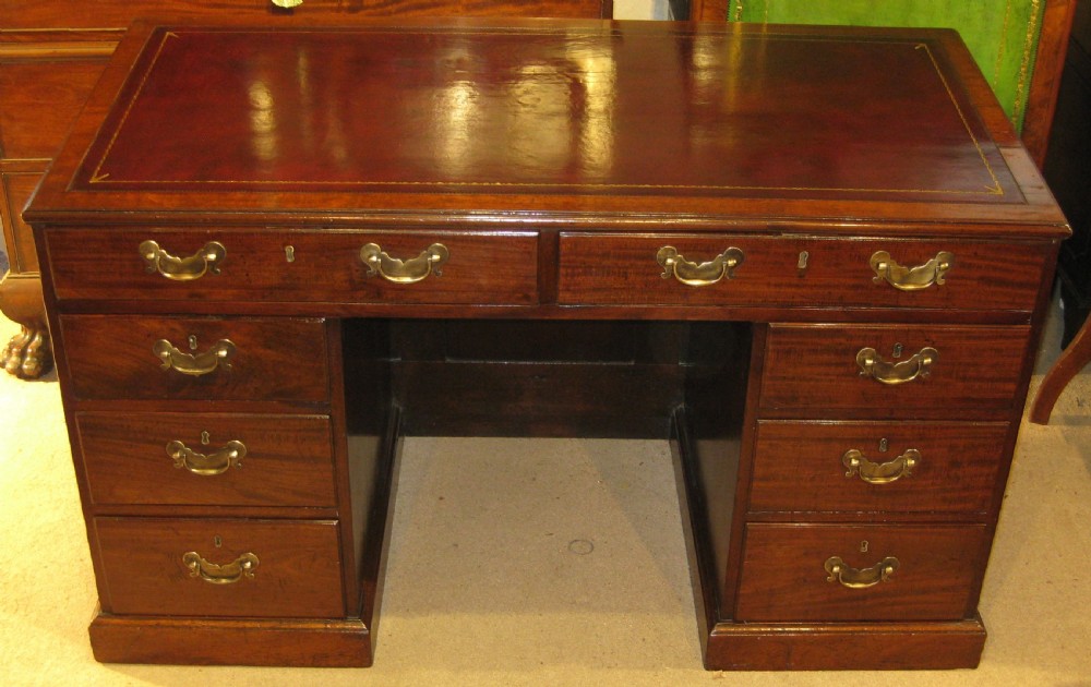 An 18th-century Georgian mahogany kneehole desk featuring a leather inset top, brass swan-neck handles, and flanking columns of drawers. View VI