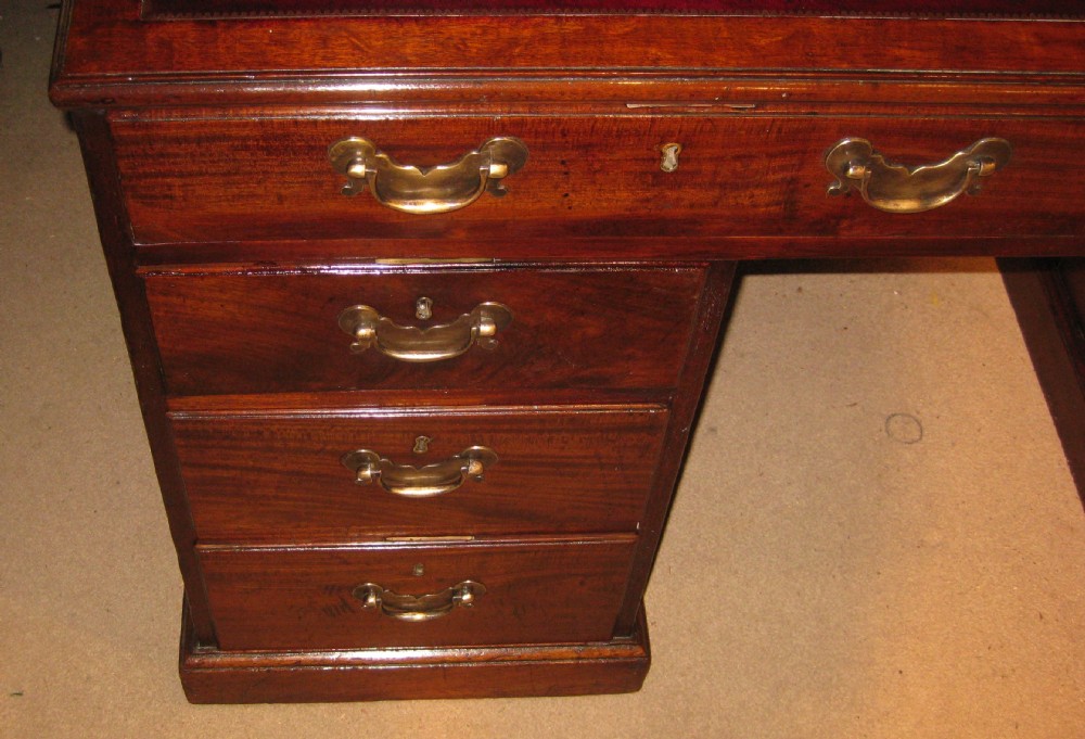 An 18th-century Georgian mahogany kneehole desk featuring a leather inset top, brass swan-neck handles, and flanking columns of drawers. View VII