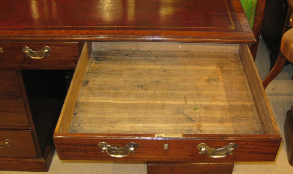 An 18th-century Georgian mahogany kneehole desk featuring a leather inset top, brass swan-neck handles, and flanking columns of drawers. View XII