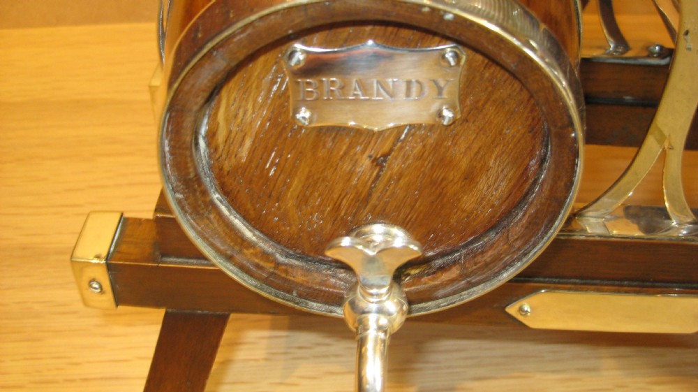 A triple miniature oak spirit barrel dispenser set mounted on a wooden frame with silver-plated hoops, spigots, and metal spirit labels. View IV