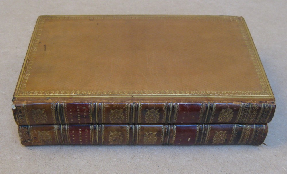 A warm brown leather box designed to resemble a book spine, opening to display marbled paper lining and two square glass inkwells. View III