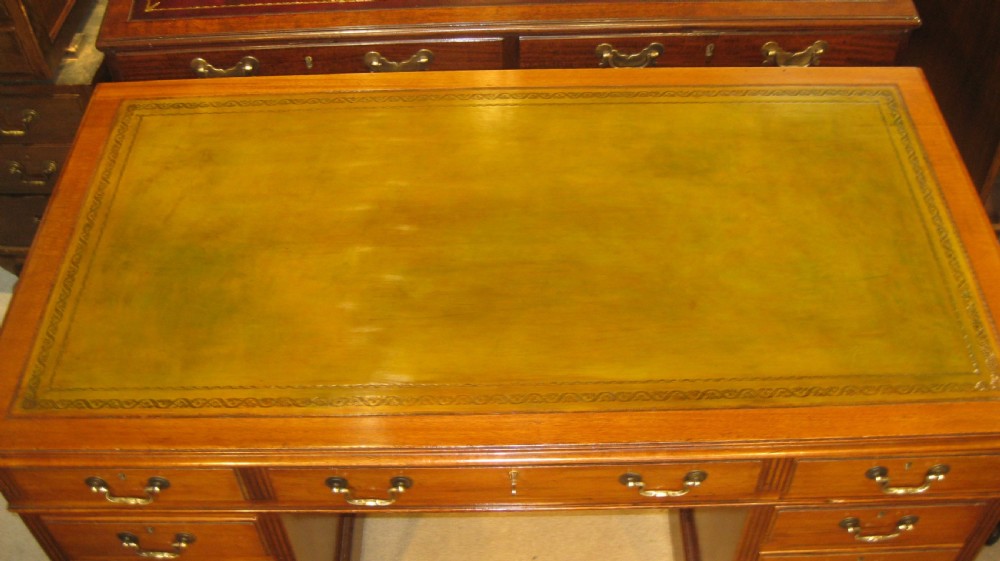 A late Victorian golden mahogany pedestal desk featuring nine drawers with brass handles and an inset leather writing top. View II