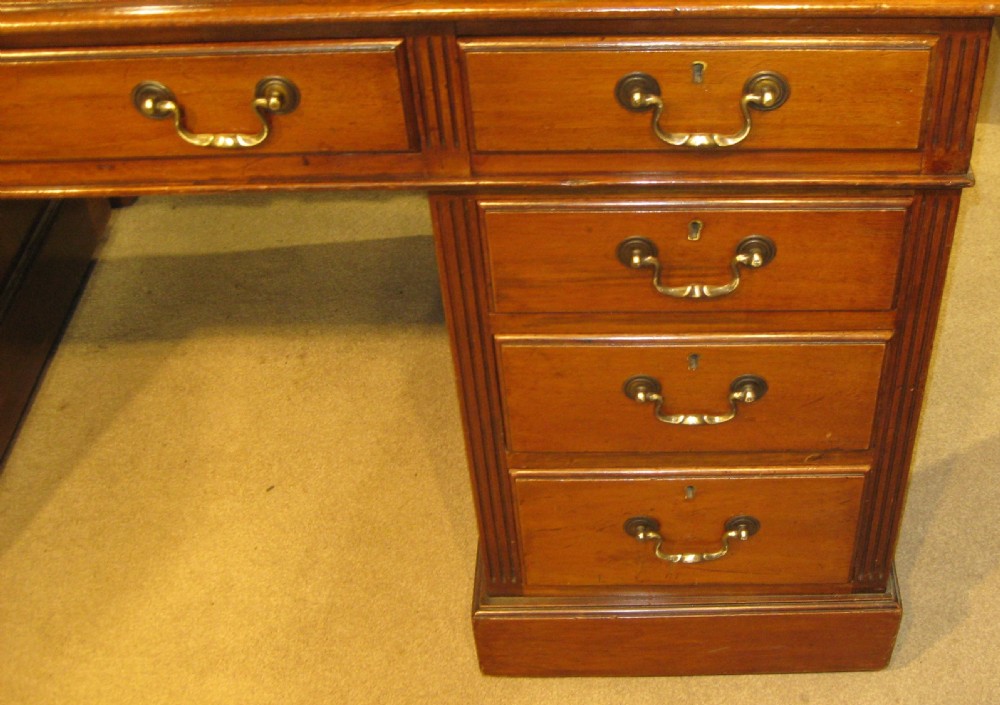 A late Victorian golden mahogany pedestal desk featuring nine drawers with brass handles and an inset leather writing top. View III