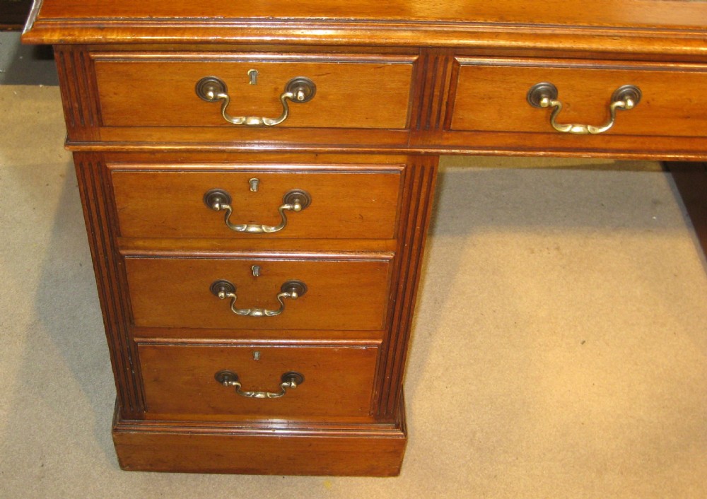 A late Victorian golden mahogany pedestal desk featuring nine drawers with brass handles and an inset leather writing top. View IV