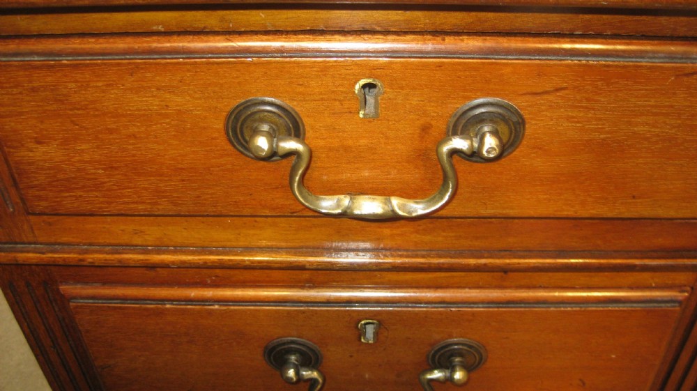 A late Victorian golden mahogany pedestal desk featuring nine drawers with brass handles and an inset leather writing top. View V