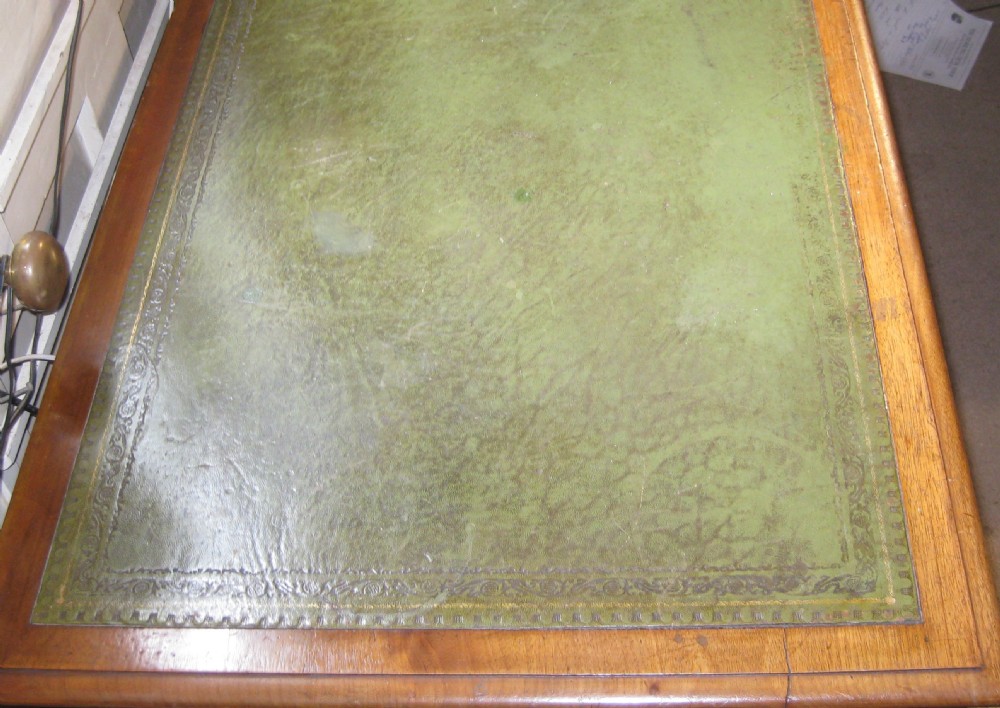 A Victorian golden mahogany pedestal desk featuring an inset green leather writing surface, nine drawers with turned wooden knobs, and a central kneehole. View IV