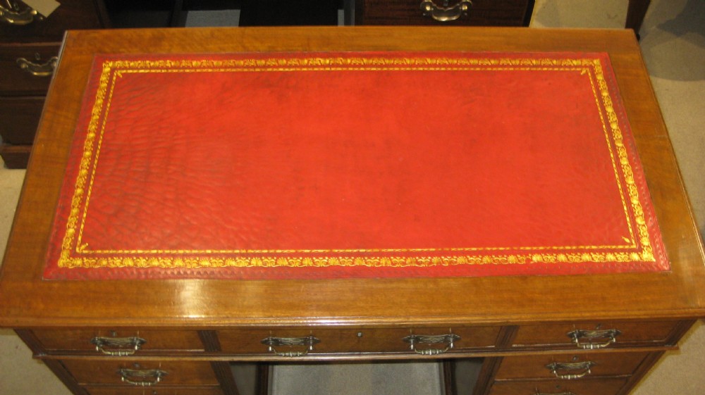 Victorian walnut pedestal desk featuring a red leather gilt-tooled inset writing surface and nine brass-handled drawers. View IV