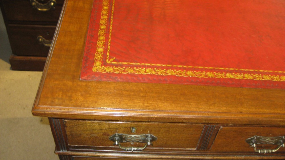 Victorian walnut pedestal desk featuring a red leather gilt-tooled inset writing surface and nine brass-handled drawers. View VII