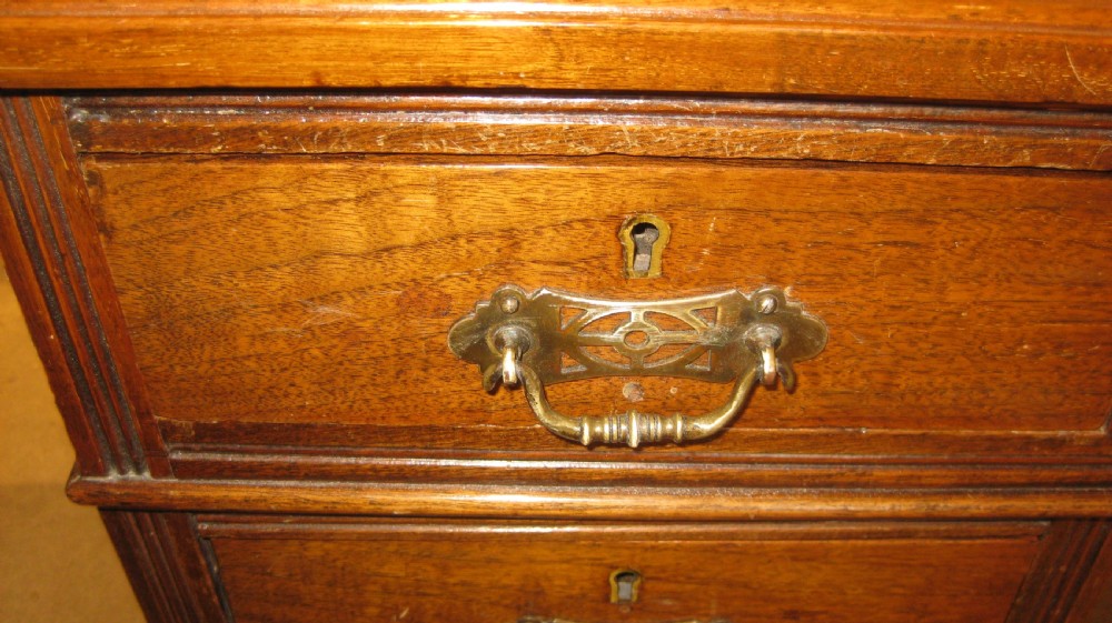Victorian walnut pedestal desk featuring a red leather gilt-tooled inset writing surface and nine brass-handled drawers. View VIII