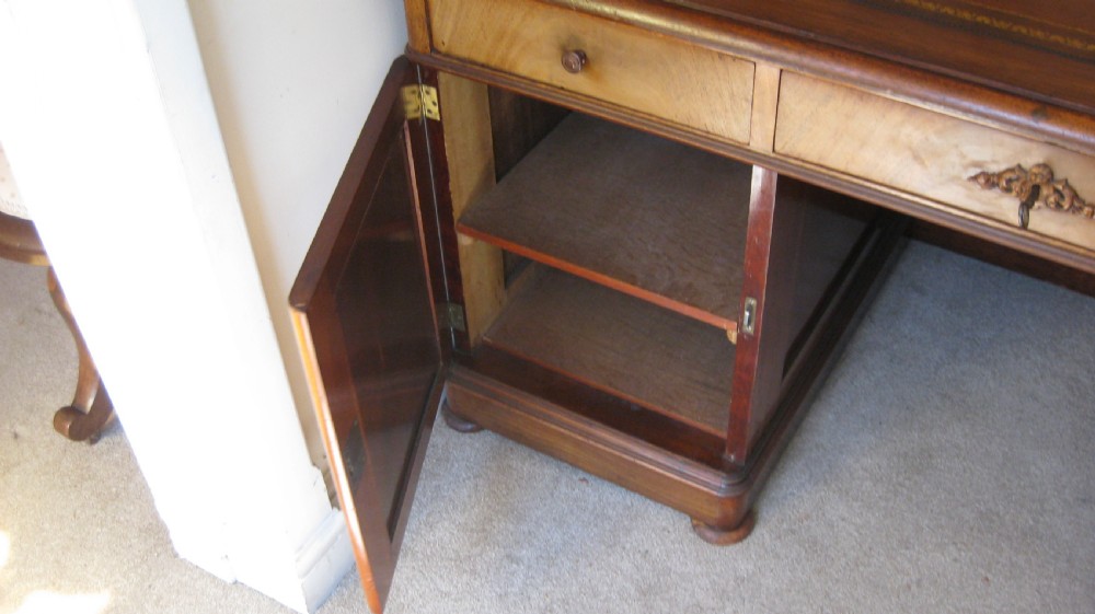 A Victorian faded mahogany pedestal desk featuring a gilt-bordered leather writing surface, three frieze drawers, and twin pedestal cupboards with arched flame mahogany panels. View III