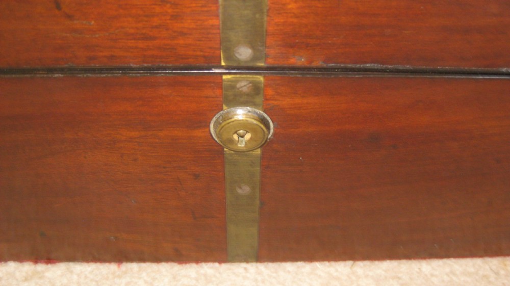 A closed rectangular dark mahogany writing box reinforced with brass straps, brass corner pieces, and a central brass keyhole. View II