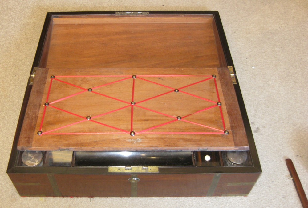 A closed rectangular dark mahogany writing box reinforced with brass straps, brass corner pieces, and a central brass keyhole. View V