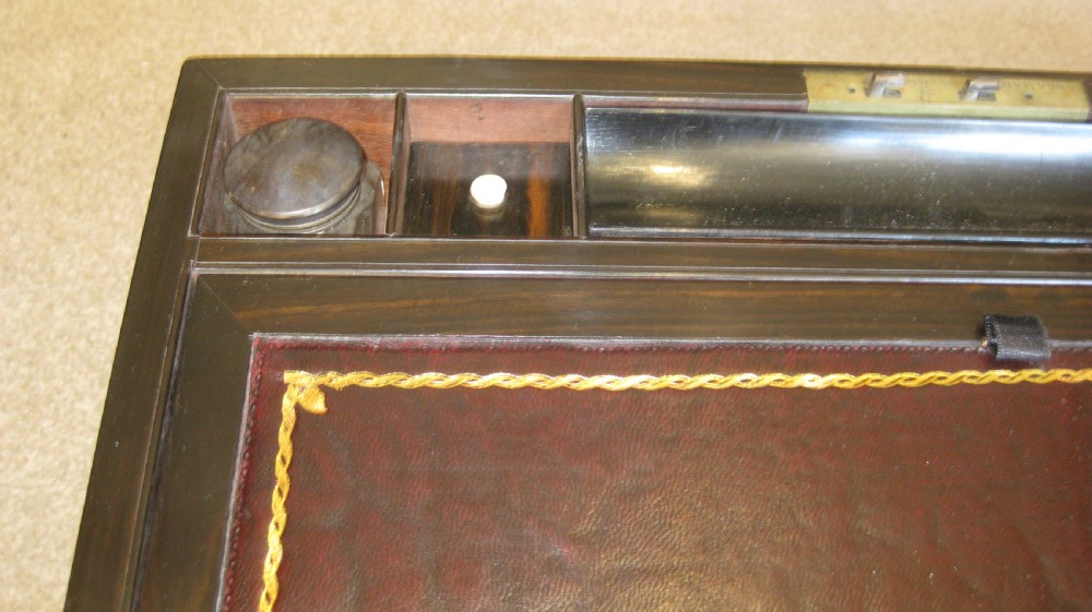 A closed rectangular dark mahogany writing box reinforced with brass straps, brass corner pieces, and a central brass keyhole. View VII