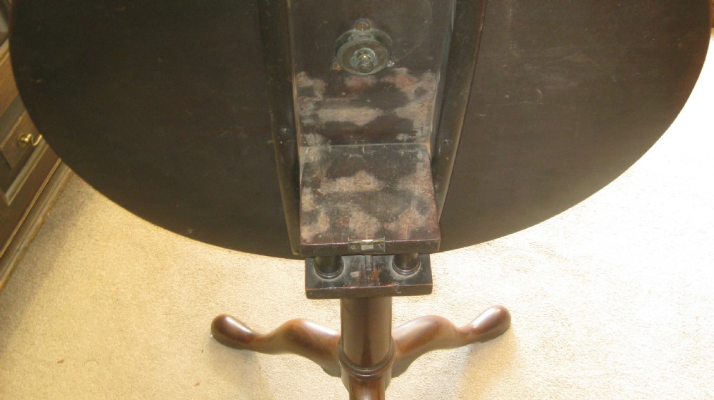 A Georgian mahogany tilt-top table shown with its circular top flipped vertically on a turned pedestal base with tripod cabriole legs. View VI