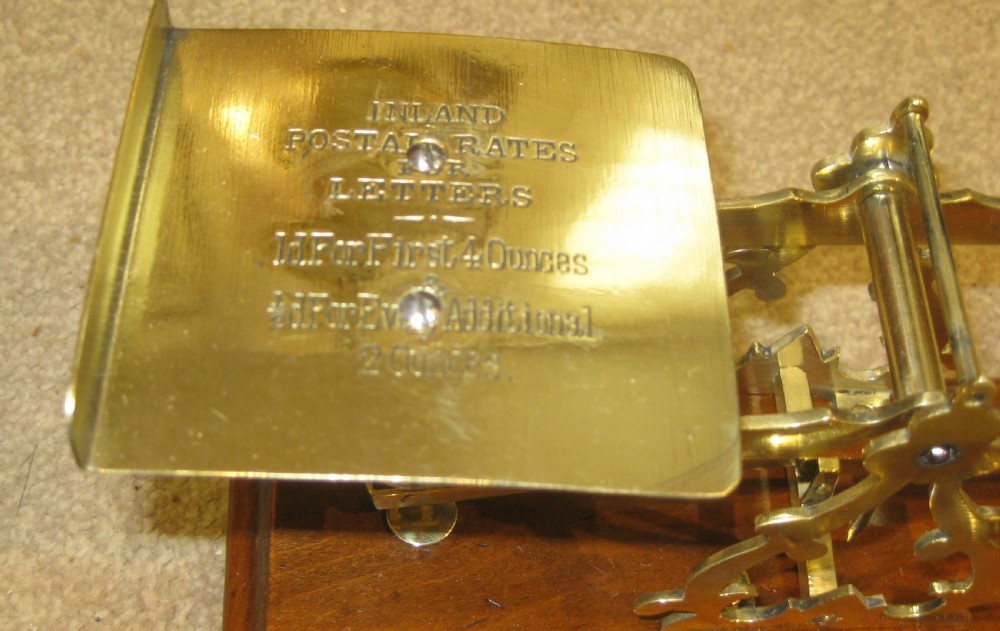 Victorian brass postal balance scale set mounted on a polished walnut wood base with tiered brass weights. View II