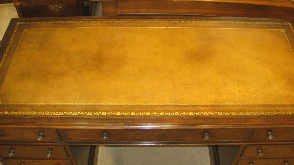 A Victorian mahogany pedestal desk featuring a tan gold-tooled leather top, nine drawers with round brass handles, and plinth bases. View III