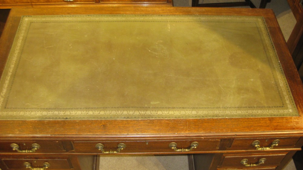 A Victorian mahogany pedestal desk featuring an olive green leather inset writing surface and nine drawers with brass handles. View III