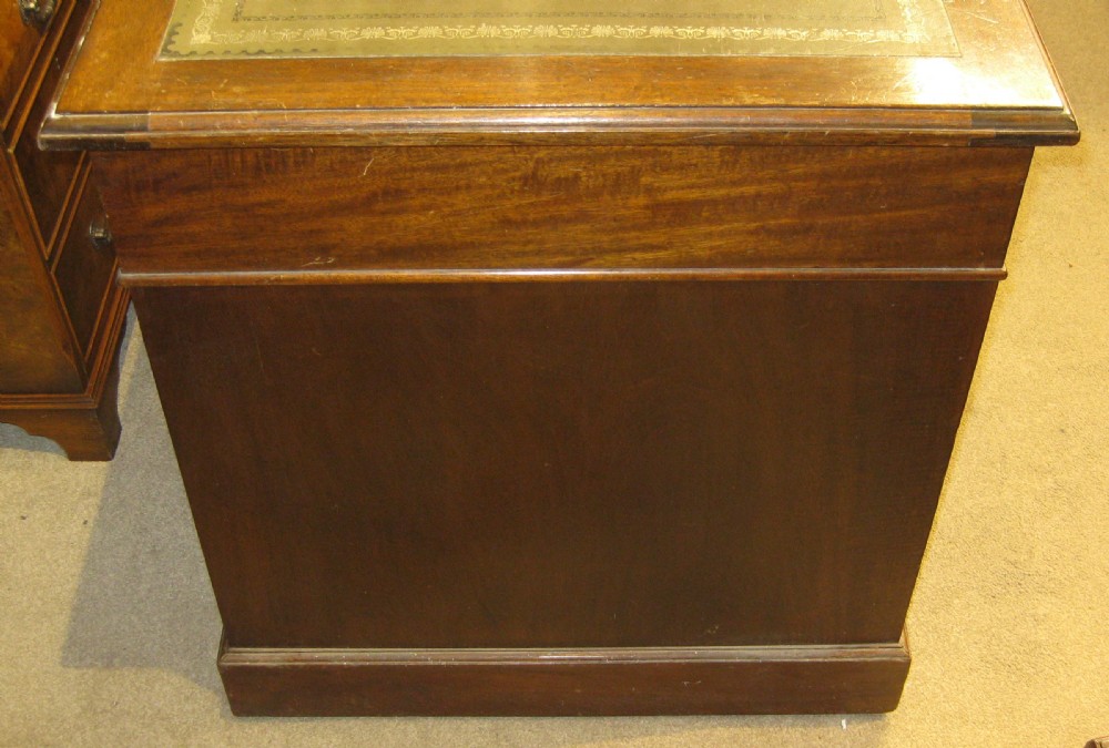 A Victorian mahogany pedestal desk featuring an olive green leather inset writing surface and nine drawers with brass handles. View IV