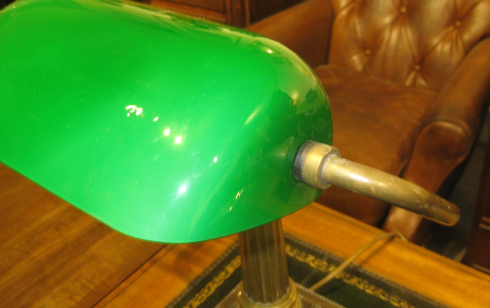 An adjustable brass desk lamp featuring a reeded stem, stepped square base, and a green glass shade. View VII