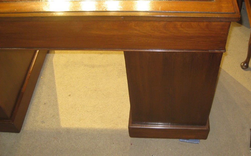 A late Victorian walnut pedestal desk featuring a gilt-tooled brown leather writing surface, nine drawers with ornate brass handles, and twin pedestals resting on plinth bases. View VII