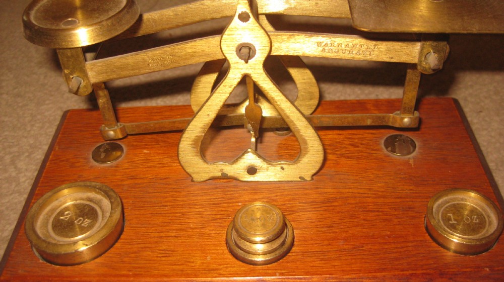 Edwardian brass balance postal scales mounted on a rectangular mahogany wooden base with recessed slots containing brass weights. View IV