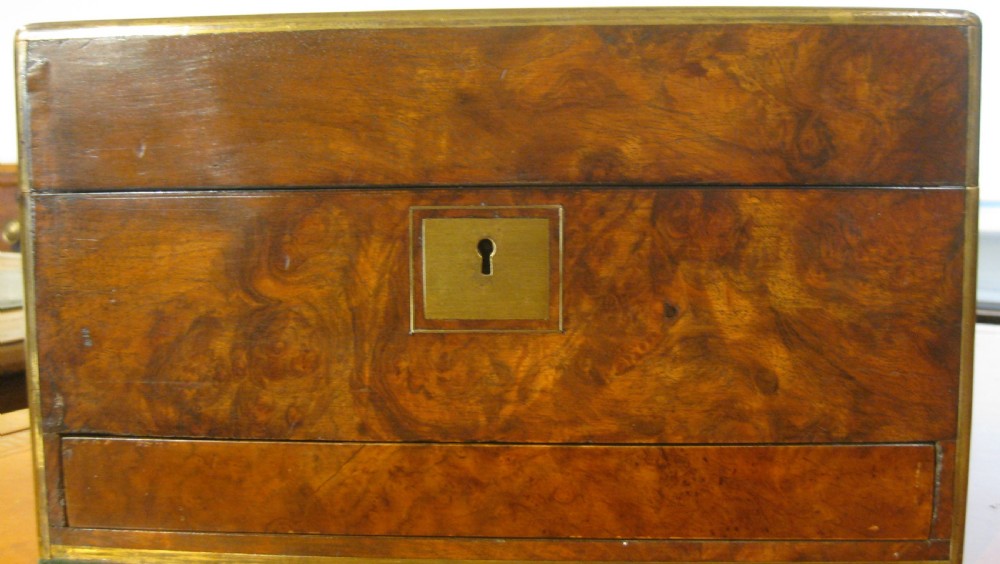 A Victorian rectangular burr walnut box featuring brass edges, a central brass cartouche, a keyhole escutcheon, and a lower drawer. View III