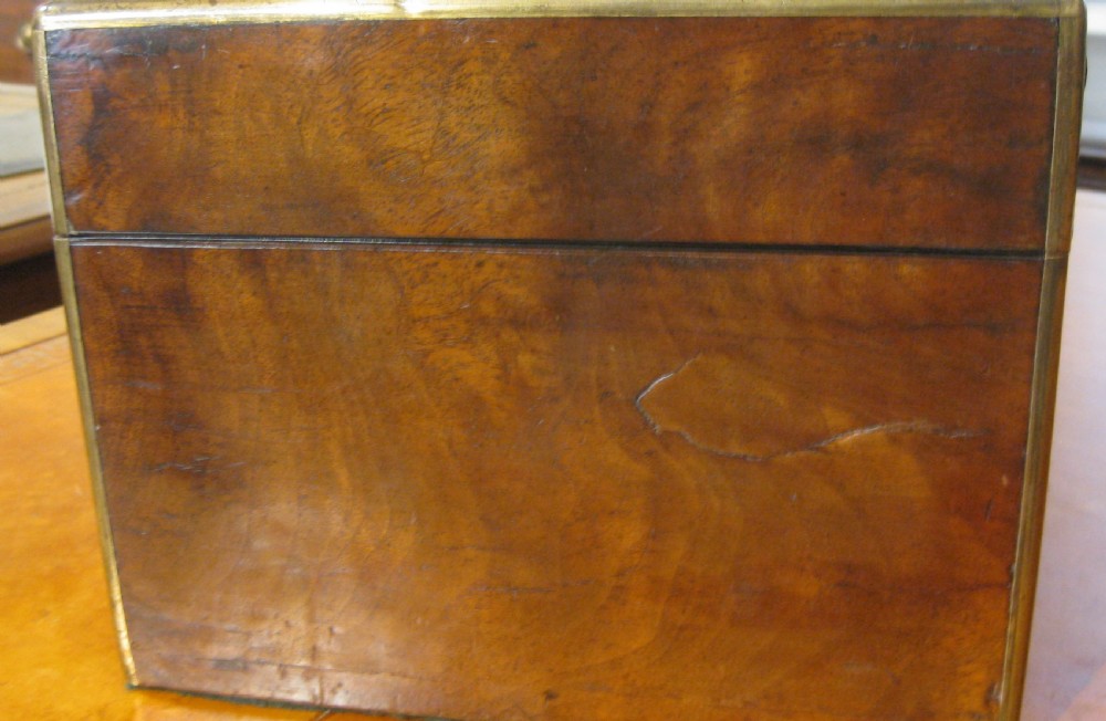 A Victorian rectangular burr walnut box featuring brass edges, a central brass cartouche, a keyhole escutcheon, and a lower drawer. View V