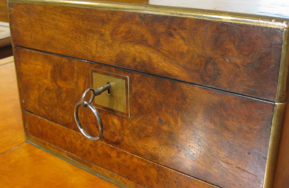 A Victorian rectangular burr walnut box featuring brass edges, a central brass cartouche, a keyhole escutcheon, and a lower drawer. View IX