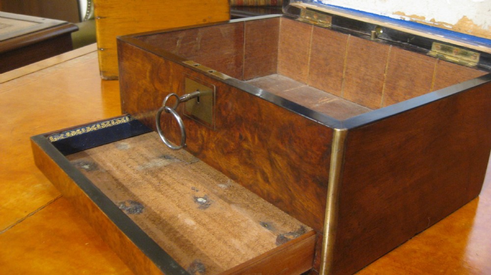 A Victorian rectangular burr walnut box featuring brass edges, a central brass cartouche, a keyhole escutcheon, and a lower drawer. View XI