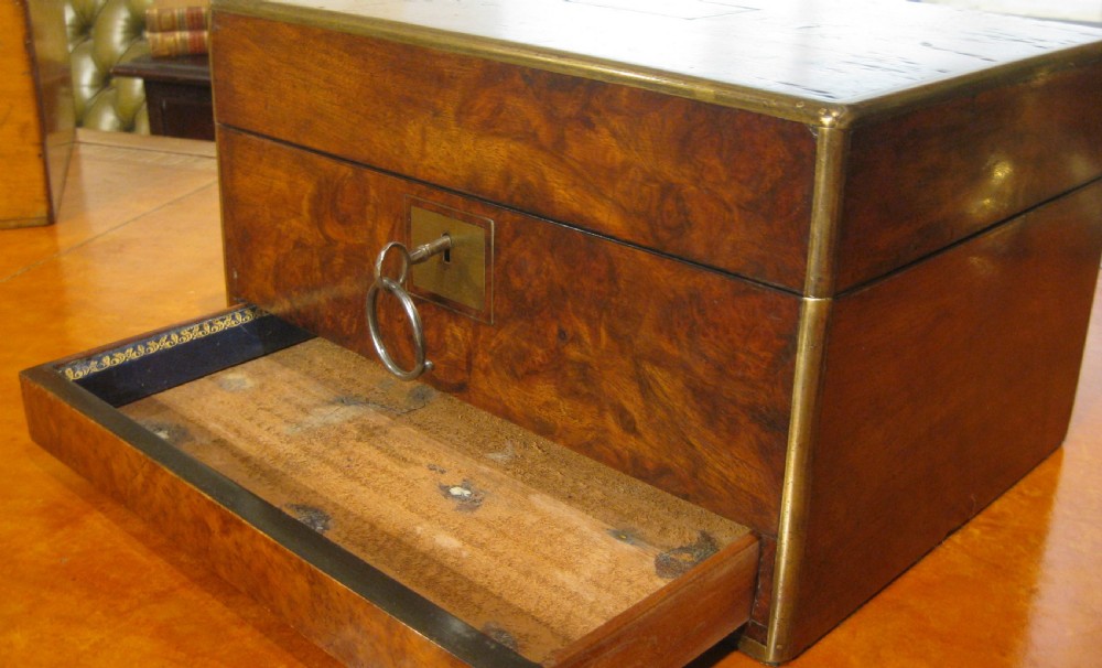 A Victorian rectangular burr walnut box featuring brass edges, a central brass cartouche, a keyhole escutcheon, and a lower drawer. View XV