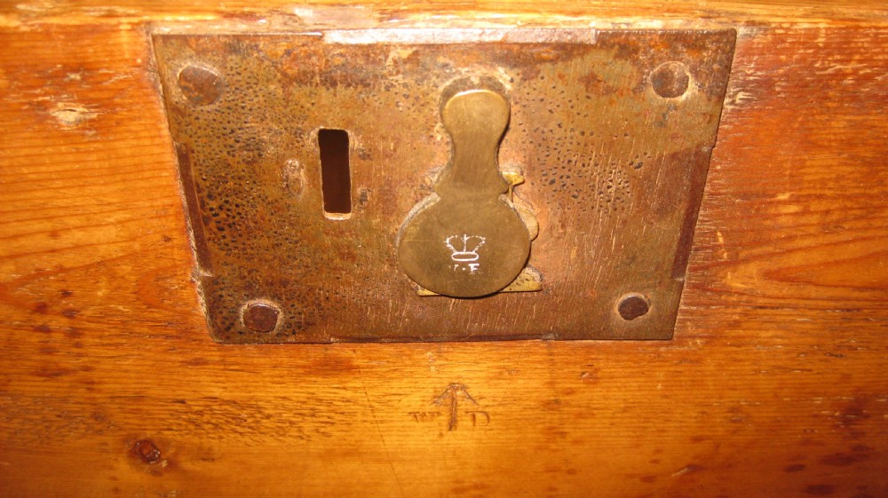A rectangular solid pine storage trunk featuring iron corner brackets and a central metal lock mechanism with key. View III